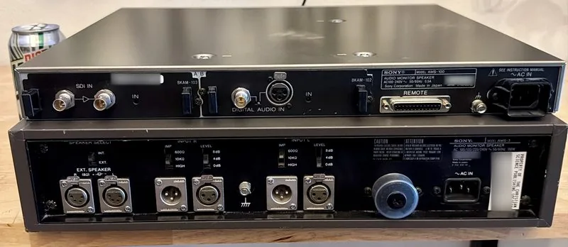 The rear panels of both units: the AMS-100's SDI and option card slots above the AMS-3's speaker terminals and XLR input bank