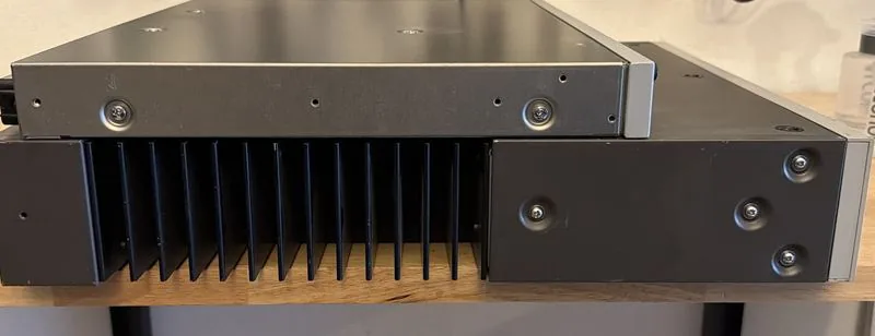 The same two Sony units from the side, the AMS-3's deep black heatsink fins running beneath the AMS-100's flat lid