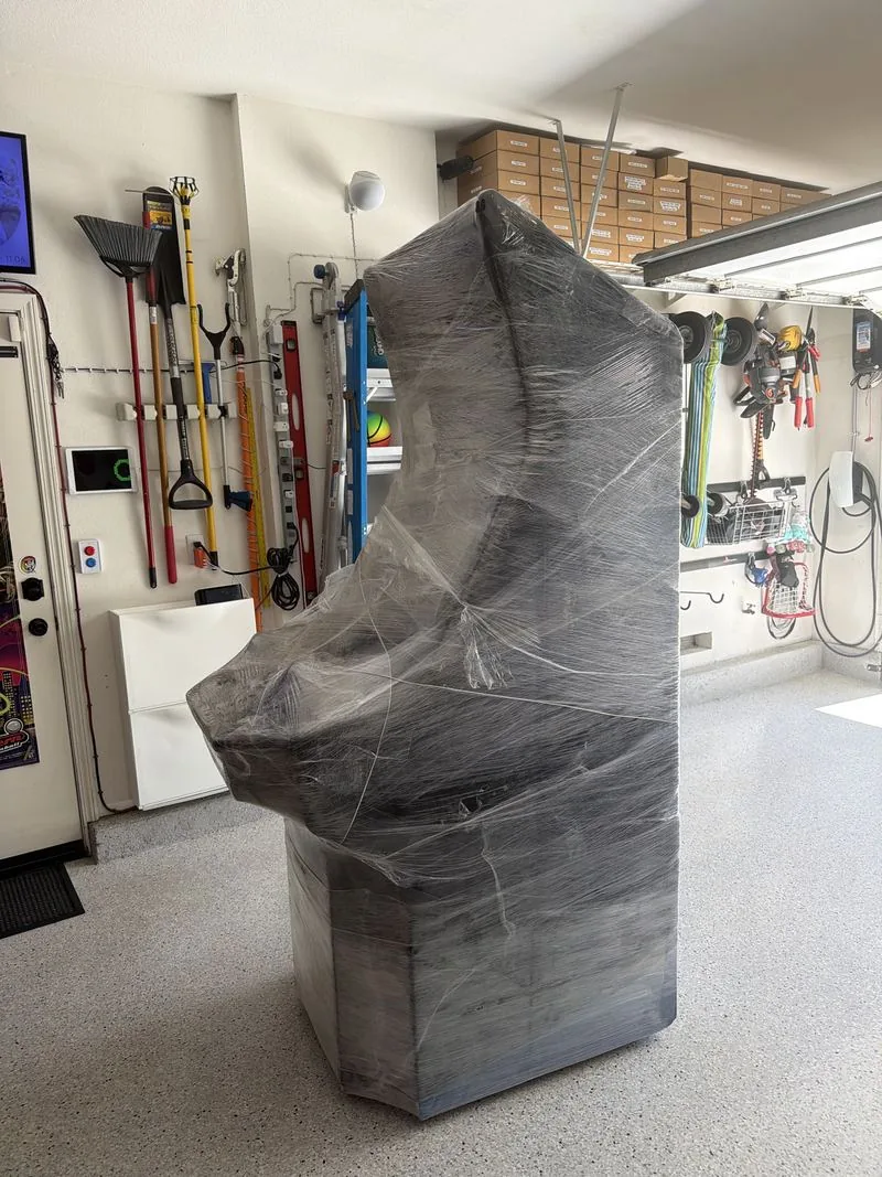 The Big Blue cabinet wrapped in plastic stretch film, standing on the garage floor the day it was delivered