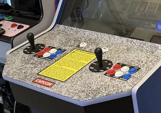 The granite-pattern control panel with two joysticks, two six-button layouts, an instruction card and a Capcom badge