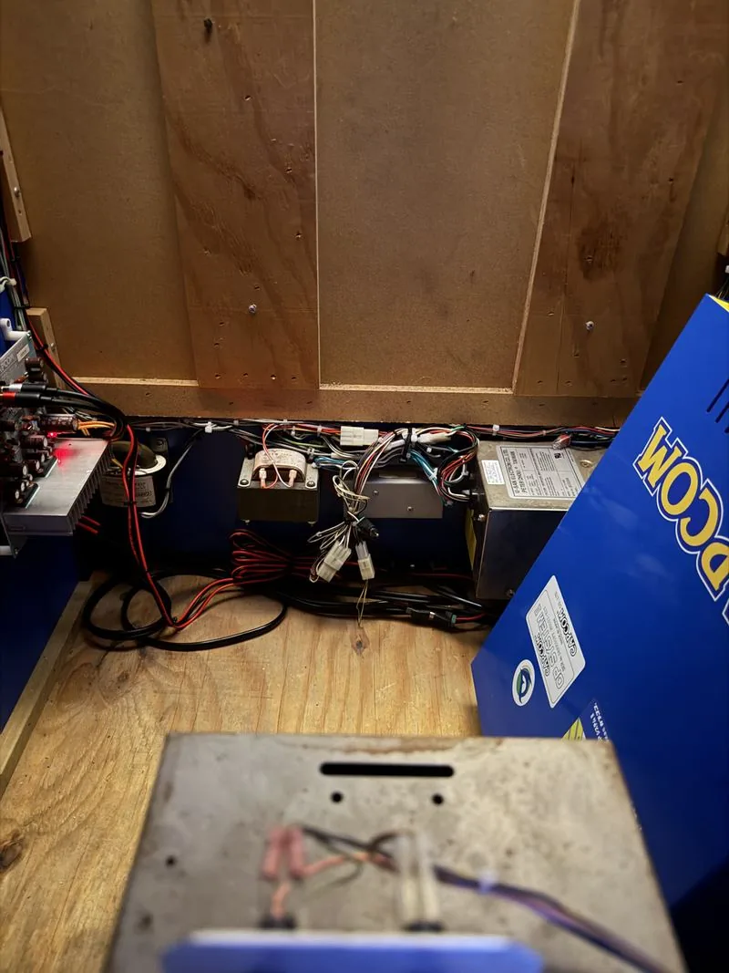 The interior of the Big Blue cabinet viewed through the coin door, showing the transformer, wiring harness and amplifier board
