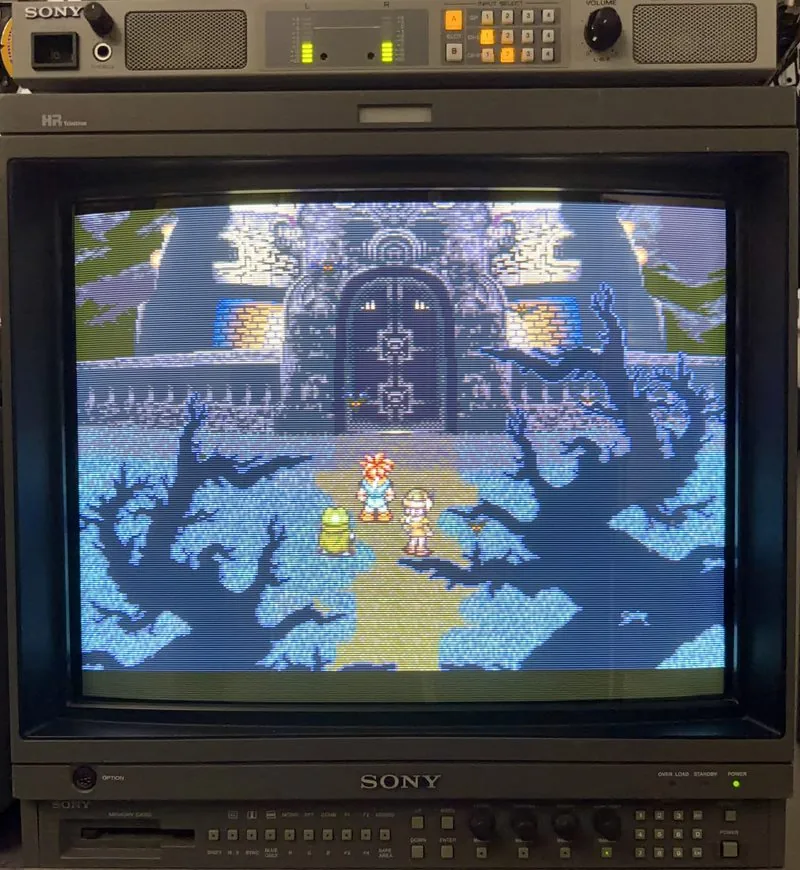 Sony BVM-20E1U broadcast monitor lit in its rack running Chrono Trigger, with an AMS-100 audio monitor speaker on top