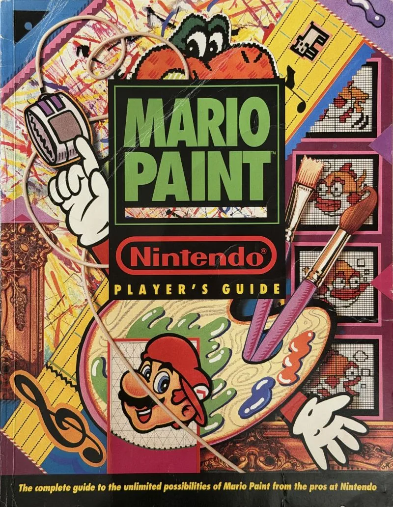 Cover of the Nintendo Player's Guide for Mario Paint, Mario holding a palette and brush beside a mouse
