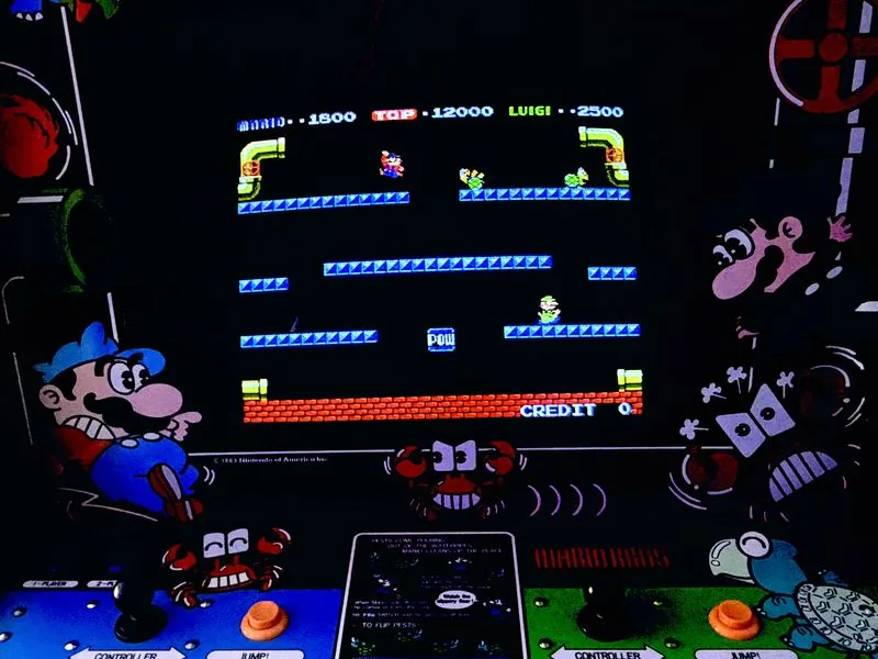 The Mario Bros. screen mid-game with the full-width control panel below it, showing the four-platform sewer level
