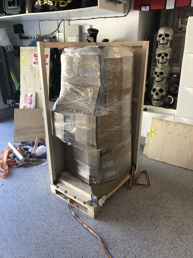 Opened crate revealing the Mini Cute wrapped in cardboard and plastic film inside the plywood frame