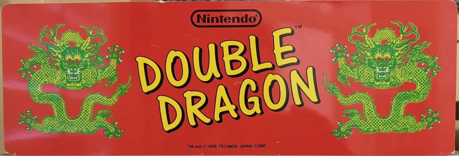 Original Nintendo PlayChoice-10 arcade topper for Double Dragon, twin green dragons on red