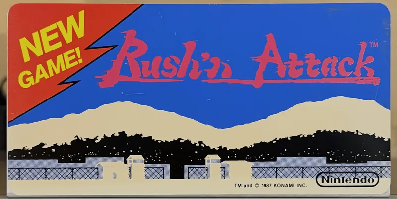 Original Nintendo PlayChoice-10 arcade topper for Rush'n Attack, red script over a blue sky and snowy mountains