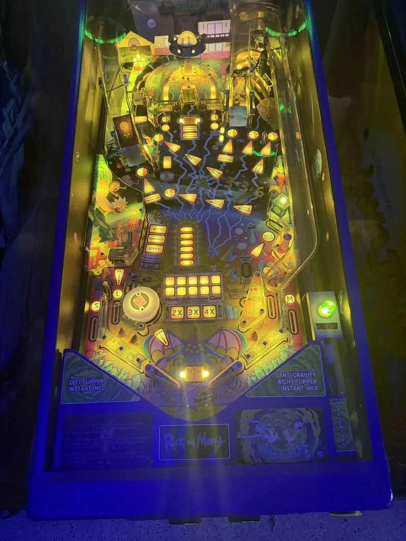 The Rick and Morty pinball playfield lit in green and gold, showing the portal and ramps