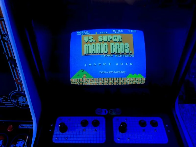 The VS. Super Mario Bros. title screen running on the Nintendo UniSystem cabinet, control panel below